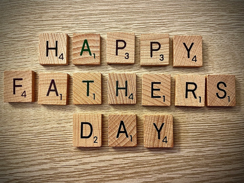 Wooden Scrabble tiles spelling out Happy Father's Day on a light wood background
